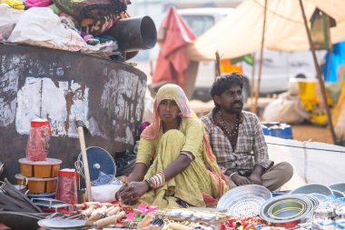 Puşkar, Rajasthan, Hindistan - 25 Kasım 2023: Puşkar Fuarı, Rajasthan 'lı Hintli bir kadının portresi, geleneksel renkli elbiseler ve başörtüsü ile sokak fuarında ürünler satışı.