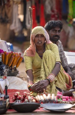 Puşkar, Rajasthan, Hindistan - 25 Kasım 2023: Puşkar Fuarı, Rajasthan 'lı Hintli bir kadının portresi, geleneksel renkli elbiseler ve başörtüsü ile sokak fuarında ürünler satışı.