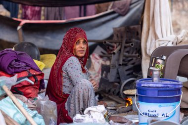 Puşkar, Rajasthan, Hindistan - 25 Kasım 2023: Puşkar Fuarı, Rajasthan 'lı Hintli bir kadının portresi, geleneksel renkli elbiseler ve başörtüsü ile sokak fuarında ürünler satışı.