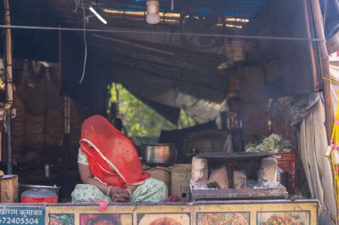 Puşkar, Rajasthan, Hindistan - 25 Kasım 2023: Puşkar Fuarı, Rajasthan 'lı Hintli bir kadının portresi, geleneksel renkli elbiseler ve başörtüsü ile sokak fuarında ürünler satışı.