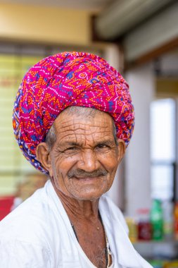 Puşkar, Rajasthan, Hindistan - 25 Kasım 2023: Puşkar Fuarı, Rajasthani 'li yaşlı bir erkeğin portresi geleneksel elbise ve renkli türbanlı bir adam.