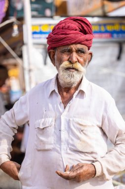 Puşkar, Rajasthan, Hindistan - 25 Kasım 2023: Puşkar Fuarı, Rajasthani 'li yaşlı bir erkeğin portresi geleneksel elbise ve renkli türbanlı bir adam.