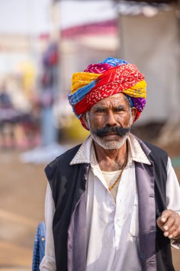 Puşkar, Rajasthan, Hindistan - 25 Kasım 2023: Puşkar Fuarı, Rajasthani 'li yaşlı bir erkeğin portresi geleneksel elbise ve renkli türbanlı bir adam.