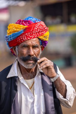 Puşkar, Rajasthan, Hindistan - 25 Kasım 2023: Puşkar Fuarı, Rajasthani 'li yaşlı bir erkeğin portresi geleneksel elbise ve renkli türbanlı bir adam.