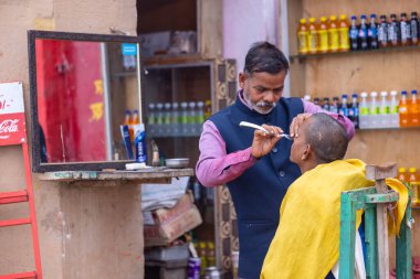 Varanasi, Uttar Pradesh, Hindistan - 05 Mart 2023: Varanasi 'deki çetelerin yakınındaki ghatlarda geleneksel giysiler giyen insanlar.