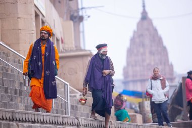 Varanasi, Uttar Pradesh, Hindistan - 05 Mart 2023: Varanasi 'deki çetelerin yakınındaki ghatlarda geleneksel giysiler giyen insanlar.