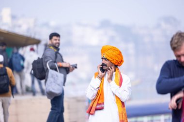 Varanasi, Uttar Pradesh, Hindistan - 19 Ocak 2024: Varanasi şehrinde geleneksel elbise içinde nehir çetelerinin yanındaki ghat üzerinde duran tanımlanamayan Hintli Brahmin erkek portresi.