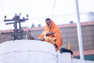 Varanasi, Uttar Pradesh, Hindistan - 19 Ocak 2024: Varanasi 'deki çetelerin yakınındaki ghatlarda oturan geleneksel bir sadhu baba resmi. Sadhu, Kaşhi 'de Ganga yakınlarında meditasyon yapıyor..