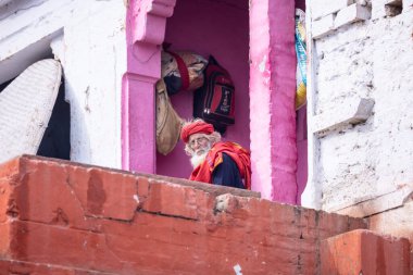 Varanasi, Uttar Pradesh, Hindistan - 19 Ocak 2024: Varanasi 'deki çetelerin yakınındaki ghatlarda oturan geleneksel bir sadhu baba resmi. Sadhu, Kaşhi 'de Ganga yakınlarında meditasyon yapıyor..