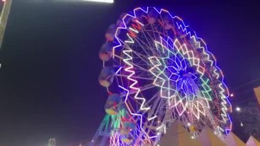 Dönme dolap ya da Joint tekerlek sürüşünün videosu yıllık fuar sırasında açık arazide mavi gökyüzünün altından geçiyor..