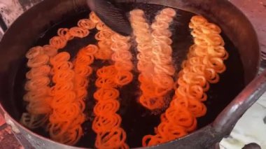 Gaziabad, Uttar Pradesh, Hindistan - 27 Ekim 2024: Şeker dükkanında Hint tatlısını hazırlayan bir erkek şefin portresi. Jalebi Hindistan 'da ve alt kıtada ünlü bir tatlıdır.. 