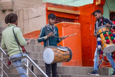 Varanasi, Uttar Pradesh, Hindistan - 05 Mart 2023: Varanasi 'deki çetelerin yakınındaki ghatlarda geleneksel giysiler giyen insanlar.