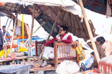 Varanasi, Uttar Pradesh, Hindistan - 19 Ocak 2024: Varanasi 'deki çetelerin yakınındaki ghatlarda şemsiye altında duran geleneksel sadhu baba resmi.