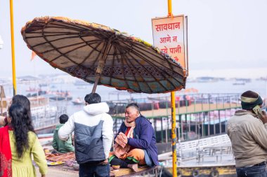 Varanasi, Uttar Pradesh, Hindistan - 19 Ocak 2024: Varanasi 'deki çetelerin yakınındaki ghatlarda geleneksel giysili insanlar