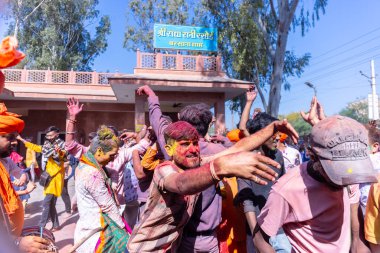 People celebrate the traditional and a ritualistic colorful Lathmar Holi with dance and colored faces at Radharani temple clipart