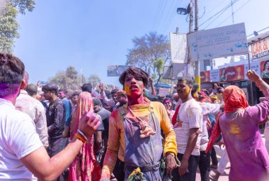 People celebrate the traditional and a ritualistic colorful Lathmar Holi with dance and colored faces at Radharani temple clipart