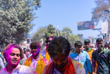 People celebrate the traditional and a ritualistic colorful Lathmar Holi with dance and colored faces at Radharani temple clipart