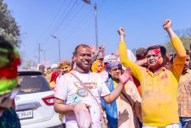 People celebrate the traditional and a ritualistic colorful Lathmar Holi with dance and colored faces at Radharani temple clipart