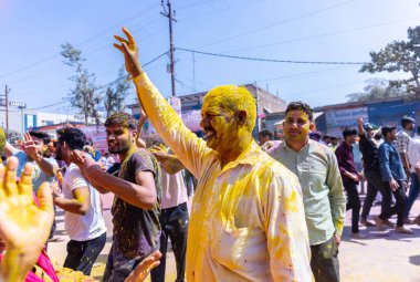 People celebrate the traditional and a ritualistic colorful Lathmar Holi with dance and colored faces at Radharani temple clipart