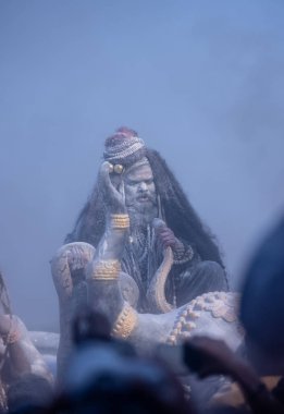 Varanasi, Uttar Pradesh, Hindistan - Mart 03 2023: Masan Holi, Harishchandra Ghat 'taki masaan Holi kutlamaları sırasında Lord Shiva gibi giyinmiş kül yüzlü bir erkek dindar portresi.
