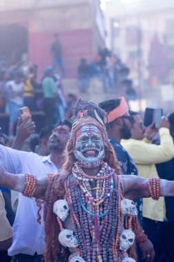 Varanasi, Uttar Pradesh, Hindistan - Mart 03 2023: Masan Holi, Harishchandra Ghat 'taki masaan Holi kutlamaları sırasında Lord Shiva gibi giyinmiş kül yüzlü bir erkek dindar portresi.