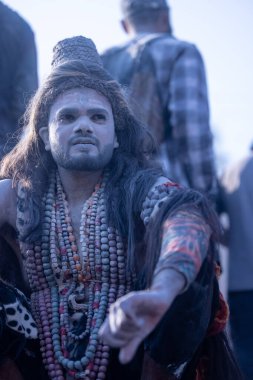 Varanasi, Uttar Pradesh, Hindistan - Mart 03 2023: Masan Holi, Harishchandra Ghat 'taki masaan Holi kutlamaları sırasında Lord Shiva gibi giyinmiş kül yüzlü bir erkek dindar portresi.