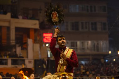 Varanasi, Uttar Pradesh, Hindistan - 19 Ocak 2024: Ganga aarti, Dashashwamedh ghat geleneksel elbise ve Hindu ayinleri ile kutsal nehir keneviri akşam ayini yapan genç bir rahibin portresi.