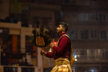 Varanasi, Uttar Pradesh, Hindistan - 19 Ocak 2024: Ganga aarti, Dashashwamedh ghat geleneksel elbise ve Hindu ayinleri ile kutsal nehir keneviri akşam ayini yapan genç bir rahibin portresi.