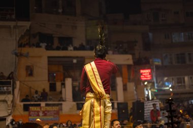 Varanasi, Uttar Pradesh, Hindistan - 19 Ocak 2024: Ganga aarti, Dashashwamedh ghat geleneksel elbise ve Hindu ayinleri ile kutsal nehir keneviri akşam ayini yapan genç bir rahibin portresi.