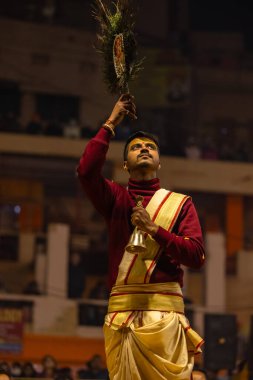 Varanasi, Uttar Pradesh, Hindistan - 19 Ocak 2024: Ganga aarti, Dashashwamedh ghat geleneksel elbise ve Hindu ayinleri ile kutsal nehir keneviri akşam ayini yapan genç bir rahibin portresi.
