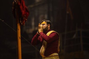 Varanasi, Uttar Pradesh, Hindistan - 19 Ocak 2024: Ganga aarti, Dashashwamedh ghat geleneksel elbise ve Hindu ayinleri ile kutsal nehir keneviri akşam ayini yapan genç bir rahibin portresi.