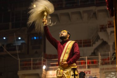 Varanasi, Uttar Pradesh, Hindistan - 19 Ocak 2024: Ganga aarti, Dashashwamedh ghat geleneksel elbise ve Hindu ayinleri ile kutsal nehir keneviri akşam ayini yapan genç bir rahibin portresi.