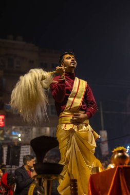 Varanasi, Uttar Pradesh, Hindistan - 19 Ocak 2024: Ganga aarti, Dashashwamedh ghat geleneksel elbise ve Hindu ayinleri ile kutsal nehir keneviri akşam ayini yapan genç bir rahibin portresi.