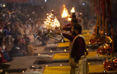 Varanasi, Uttar Pradesh, Hindistan - 19 Ocak 2024: Ganga aarti, Dashashwamedh ghat geleneksel elbise ve Hindu ayinleri ile kutsal nehir keneviri akşam ayini yapan genç bir rahibin portresi.