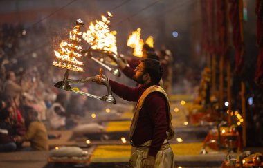 Varanasi, Uttar Pradesh, Hindistan - 19 Ocak 2024: Ganga aarti, Dashashwamedh ghat geleneksel elbise ve Hindu ayinleri ile kutsal nehir keneviri akşam ayini yapan genç bir rahibin portresi.
