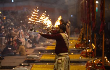 Varanasi, Uttar Pradesh, Hindistan - 19 Ocak 2024: Ganga aarti, Dashashwamedh ghat geleneksel elbise ve Hindu ayinleri ile kutsal nehir keneviri akşam ayini yapan genç bir rahibin portresi.