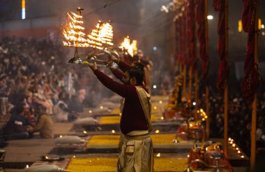 Varanasi, Uttar Pradesh, Hindistan - 19 Ocak 2024: Ganga aarti, Dashashwamedh ghat geleneksel elbise ve Hindu ayinleri ile kutsal nehir keneviri akşam ayini yapan genç bir rahibin portresi.