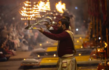 Varanasi, Uttar Pradesh, Hindistan - 19 Ocak 2024: Ganga aarti, Dashashwamedh ghat geleneksel elbise ve Hindu ayinleri ile kutsal nehir keneviri akşam ayini yapan genç bir rahibin portresi.
