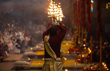 Varanasi, Uttar Pradesh, Hindistan - 19 Ocak 2024: Ganga aarti, Dashashwamedh ghat geleneksel elbise ve Hindu ayinleri ile kutsal nehir keneviri akşam ayini yapan genç bir rahibin portresi.