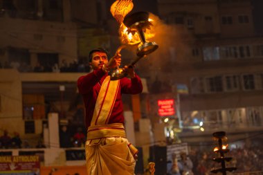 Varanasi, Uttar Pradesh, Hindistan - 19 Ocak 2024: Ganga aarti, Dashashwamedh ghat geleneksel elbise ve Hindu ayinleri ile kutsal nehir keneviri akşam ayini yapan genç bir rahibin portresi.