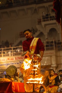 Varanasi, Uttar Pradesh, Hindistan - 19 Ocak 2024: Ganga aarti, Dashashwamedh ghat geleneksel elbise ve Hindu ayinleri ile kutsal nehir keneviri akşam ayini yapan genç bir rahibin portresi.