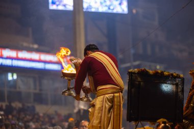 Varanasi, Uttar Pradesh, Hindistan - 19 Ocak 2024: Ganga aarti, Dashashwamedh ghat geleneksel elbise ve Hindu ayinleri ile kutsal nehir keneviri akşam ayini yapan genç bir rahibin portresi.