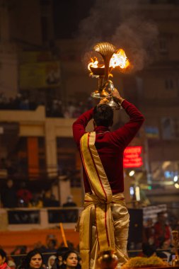 Varanasi, Uttar Pradesh, Hindistan - 19 Ocak 2024: Ganga aarti, Dashashwamedh ghat geleneksel elbise ve Hindu ayinleri ile kutsal nehir keneviri akşam ayini yapan genç bir rahibin portresi.