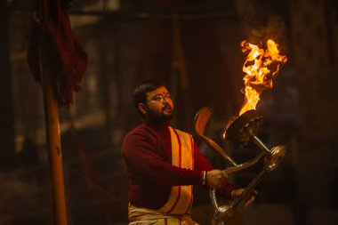 Varanasi, Uttar Pradesh, Hindistan - 19 Ocak 2024: Ganga aarti, Dashashwamedh ghat geleneksel elbise ve Hindu ayinleri ile kutsal nehir keneviri akşam ayini yapan genç bir rahibin portresi.
