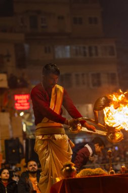 Varanasi, Uttar Pradesh, Hindistan - 19 Ocak 2024: Ganga aarti, Dashashwamedh ghat geleneksel elbise ve Hindu ayinleri ile kutsal nehir keneviri akşam ayini yapan genç bir rahibin portresi.