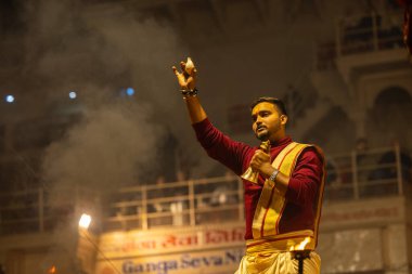 Varanasi, Uttar Pradesh, Hindistan - 19 Ocak 2024: Ganga aarti, Dashashwamedh ghat geleneksel elbise ve Hindu ayinleri ile kutsal nehir keneviri akşam ayini yapan genç bir rahibin portresi.