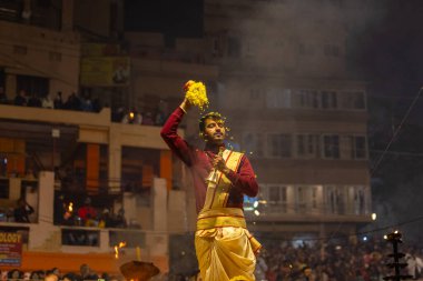 Varanasi, Uttar Pradesh, Hindistan - 19 Ocak 2024: Ganga aarti, Dashashwamedh ghat geleneksel elbise ve Hindu ayinleri ile kutsal nehir keneviri akşam ayini yapan genç bir rahibin portresi.