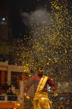 Varanasi, Uttar Pradesh, Hindistan - 19 Ocak 2024: Ganga aarti, Dashashwamedh ghat geleneksel elbise ve Hindu ayinleri ile kutsal nehir keneviri akşam ayini yapan genç bir rahibin portresi.