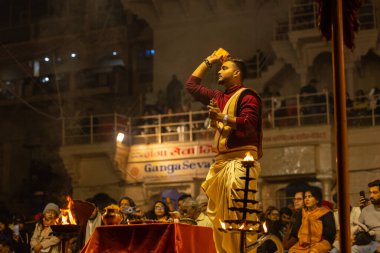 Varanasi, Uttar Pradesh, Hindistan - 19 Ocak 2024: Ganga aarti, Dashashwamedh ghat geleneksel elbise ve Hindu ayinleri ile kutsal nehir keneviri akşam ayini yapan genç bir rahibin portresi.