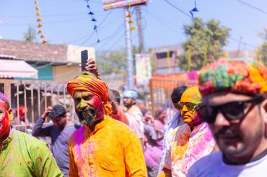 Barsana, Uttar Pradesh, Hindistan - 18 Mart 2024: Barsana sokaklarındaki Holi festivalini kuru organik renklerle kutlayan Hindu dindar grup.